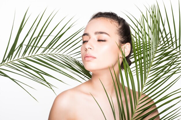 Young beautiful woman posing with green palm leaves