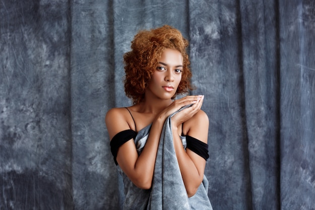 Young beautiful woman posing, wrapping up  in grey cloth