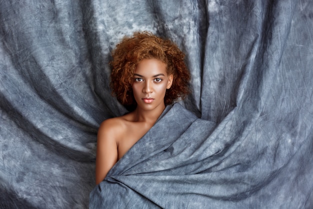 Free photo young beautiful woman posing, wrapping up  in grey cloth