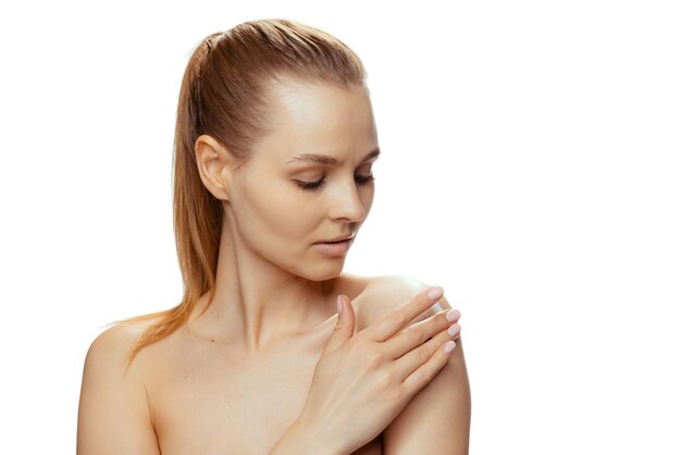 Young beautiful woman putting moisturizing cream on body isolated over white studio background
