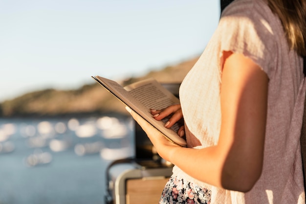 Free photo young beautiful woman reading by the lake