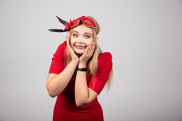 Young beautiful woman in red mask holding her face.