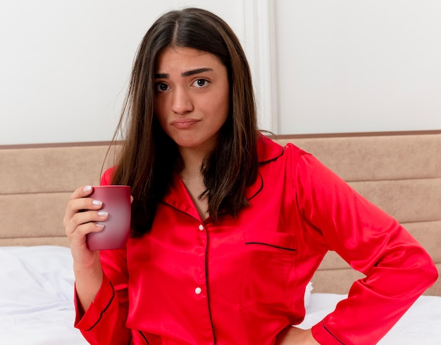 Young beautiful woman in red pajamas relaxing in bed