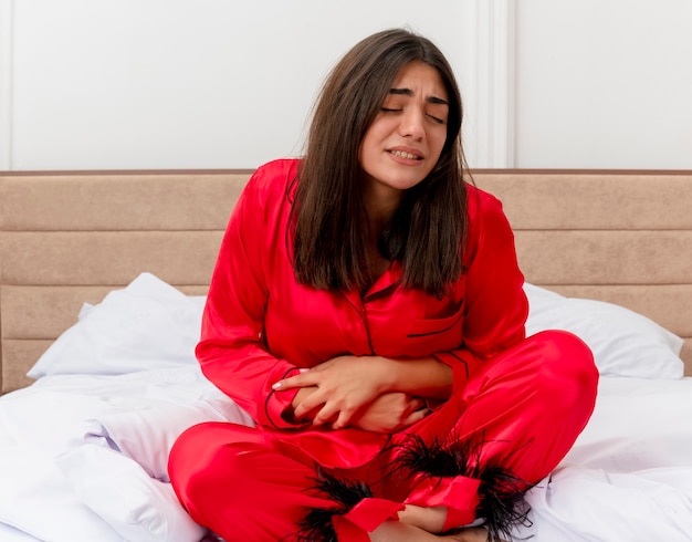 Free photo young beautiful woman in red pajamas relaxing in bed