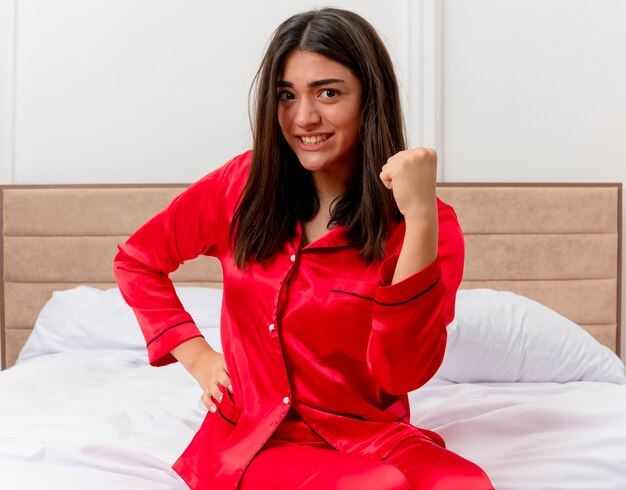 ベッドでリラックスして赤いパジャマの若い美しい女性