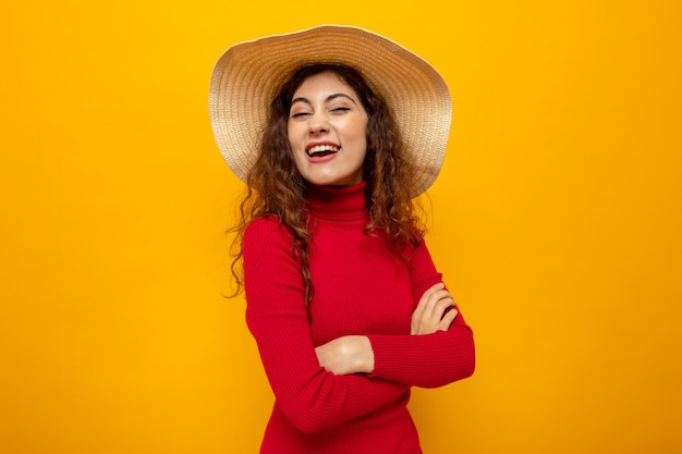 Young beautiful woman in red turtleneck in summer hat looking happy and cheerful smiling broadly