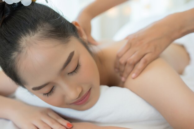 Young beautiful woman relaxing during massage in spa salon.