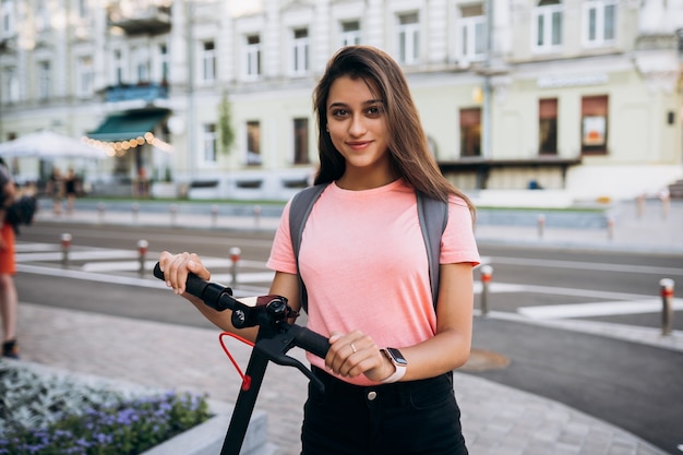 電動スクーターに乗っている若い美しい女性、生態系の輸送で現代の女の子。