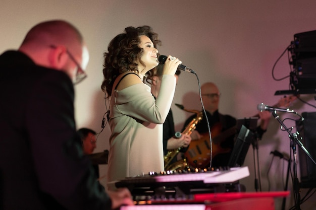 Cantante giovane e bella donna sul palco che canta nel microfono