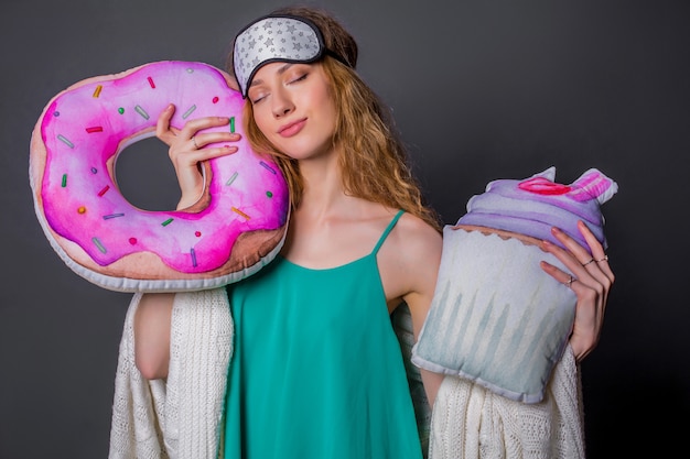 Young beautiful woman in sleepwear with funny cushions