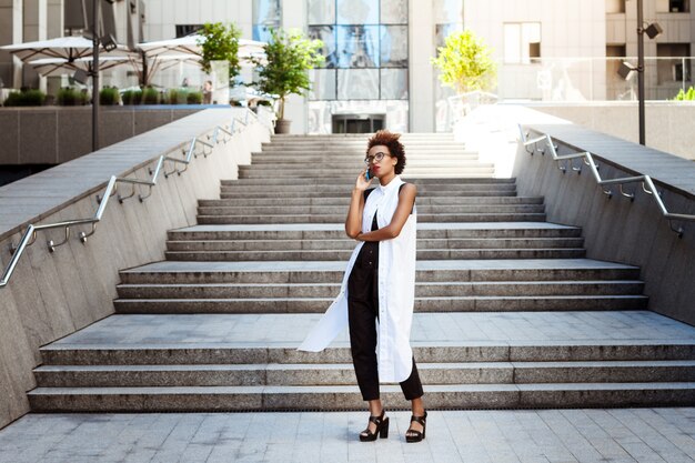 Young beautiful woman speaking on phone walking down city