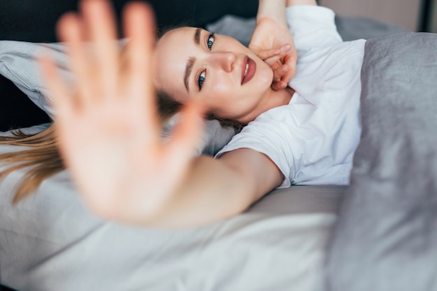 Young beautiful woman stretching while waking in the morning up fully rested