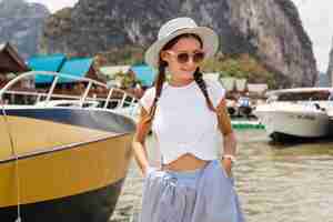 Foto gratuita giovane bella donna in abito di moda estiva, stile casual, in viaggio con zaino, cappello, occhiali da sole, vacanze in thailandia, asia