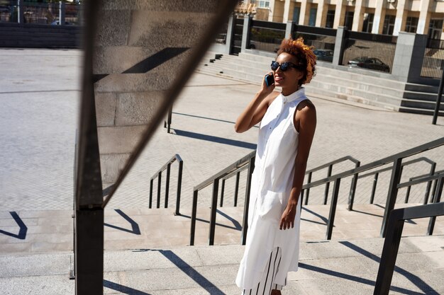 Young beautiful woman talking on phone walking down city