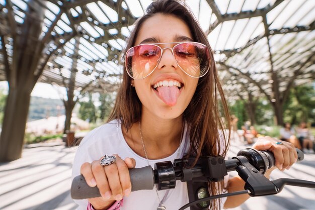 young beautiful woman teasing and showing tongue in the park