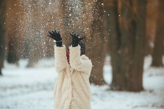 Young beautiful woman throws snow over head