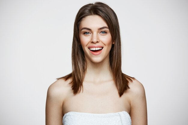 Young beautiful woman in towel with natural make up smiling. Cosmetology and spa. Facial treatment.