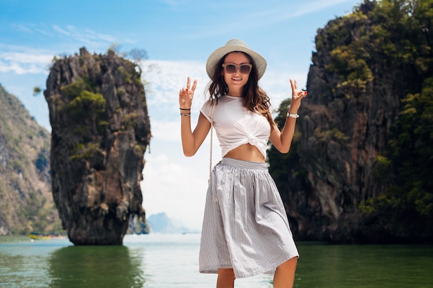 Young beautiful woman traveling in thailand, summer vacation, casual style, sunglasses, hat, cotton skirt, t-shirt, smiling, happy, adventures