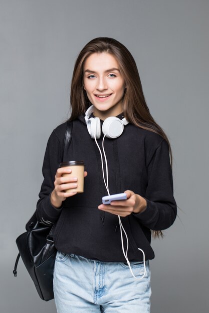 Young beautiful woman using smart phone isolated on gray wall