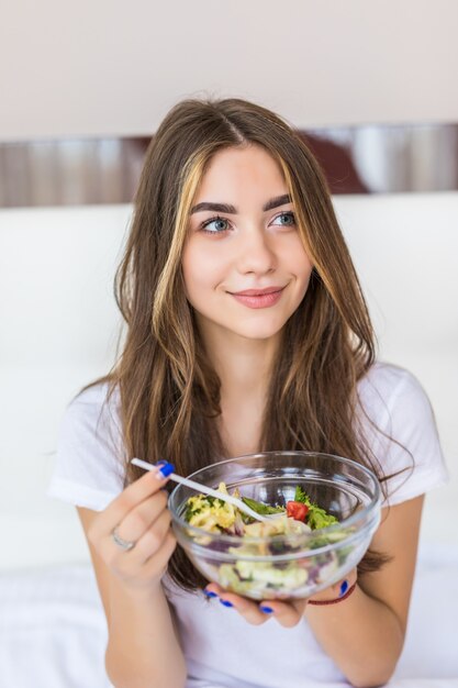 家で新鮮なグリーンサラダを食べる若い美しい女性菜食主義者