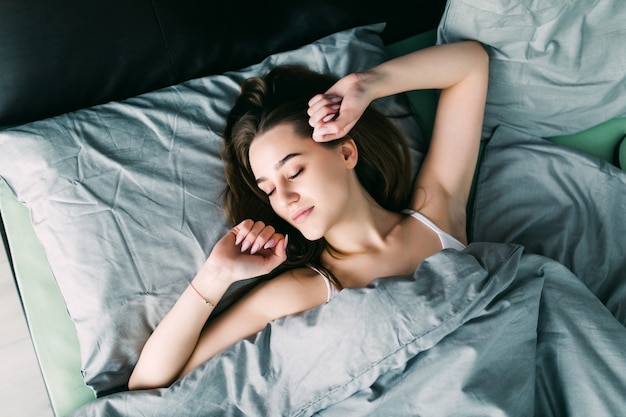 Young beautiful woman waking up in her bed fully rested