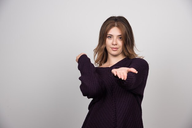 Young beautiful woman in warm knitted sweater showing her hand.
