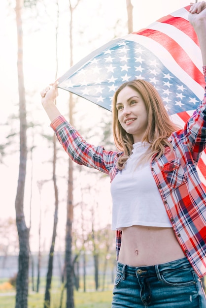 Young beautiful woman waving flag of USA