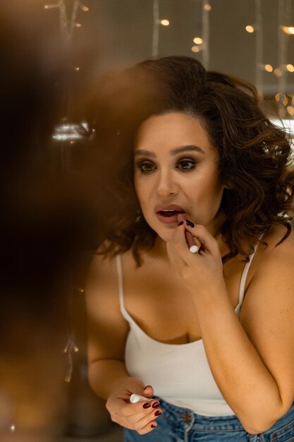 young beautiful woman wearing makeup looking in the mirror