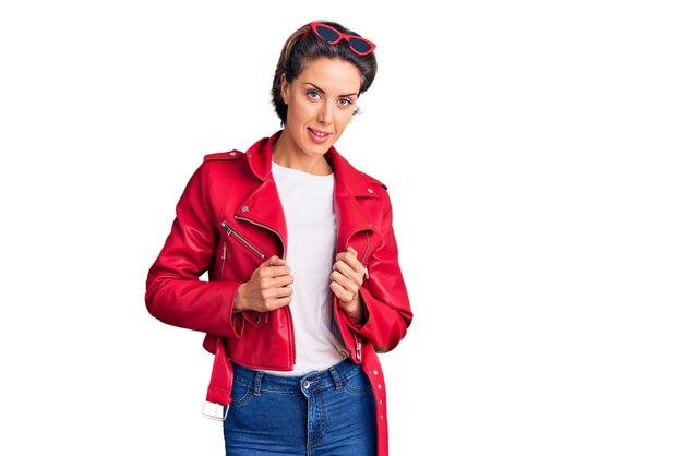 Young beautiful woman wearing red leather jacket relaxed with serious expression on face. simple and natural looking at the camera.