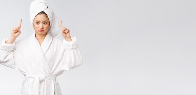 Young beautiful woman wearing shower towel after bath over isolated white background pointing with finger