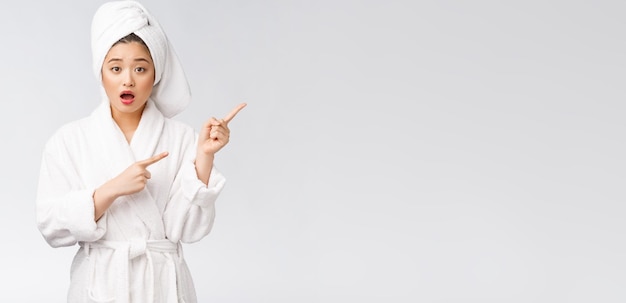 Young beautiful woman wearing shower towel after bath over isolated white background pointing with finger