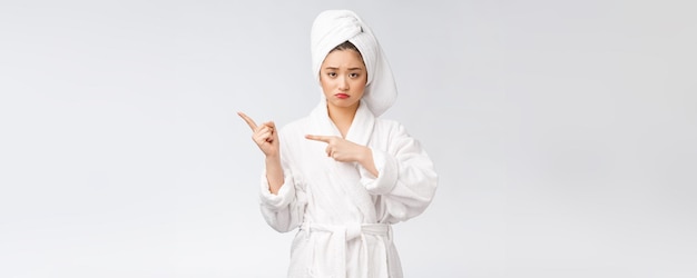 Free photo young beautiful woman wearing shower towel after bath over isolated white background pointing with finger