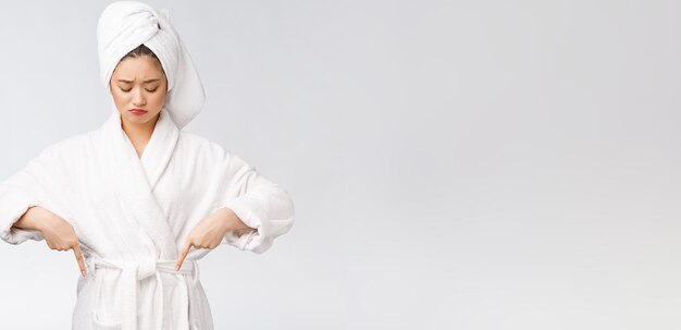 Young beautiful woman wearing shower towel after bath over isolated white background pointing with finger