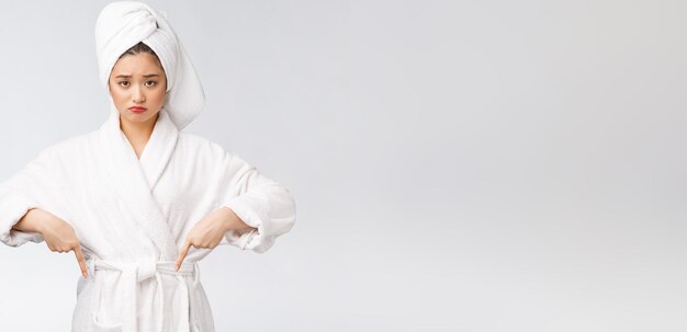 Young beautiful woman wearing shower towel after bath over isolated white background pointing with finger