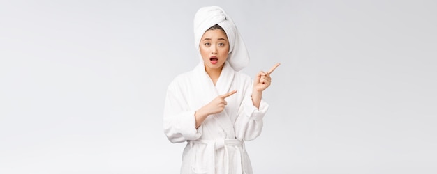 Young beautiful woman wearing shower towel after bath over isolated white background pointing with finger