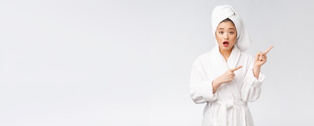 Young beautiful woman wearing shower towel after bath over isolated white background pointing with finger