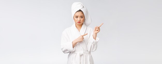 Young beautiful woman wearing shower towel after bath over isolated white background pointing with finger