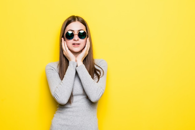 Young beautiful woman wearing summer style and sunglasses over yellow isolated wall touching mouth with hand with painful expression because of toothache