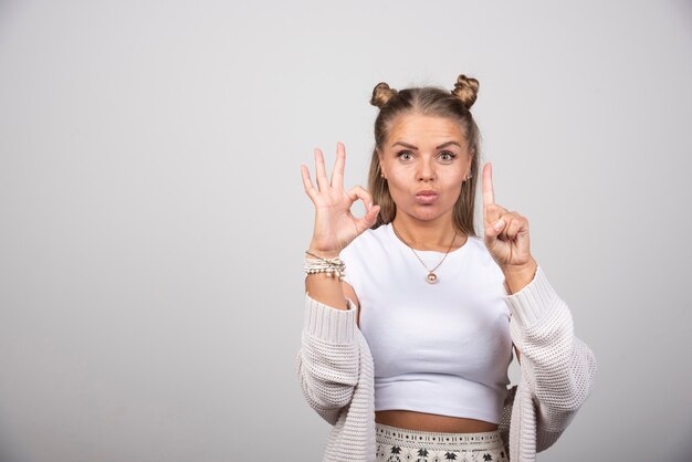 Free photo young beautiful woman in white outfit giving ok sign.