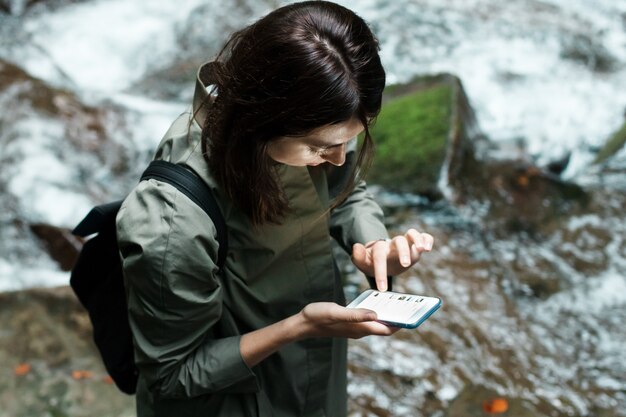 Young beautiful woman with backpack looking at phone