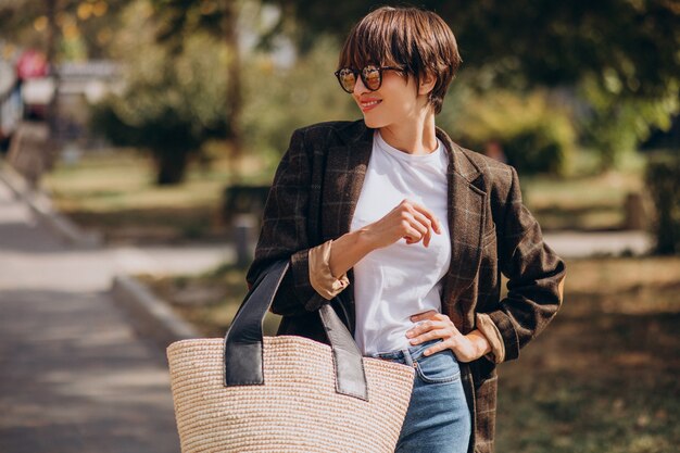 通りの外でバッグを持つ若い美しい女性