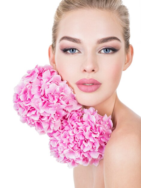 Young beautiful woman with flowers near face.