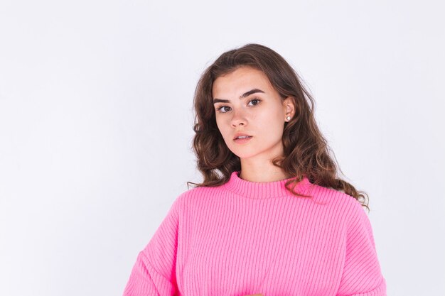 Young beautiful woman with freckles light makeup in sweater on white wall posing