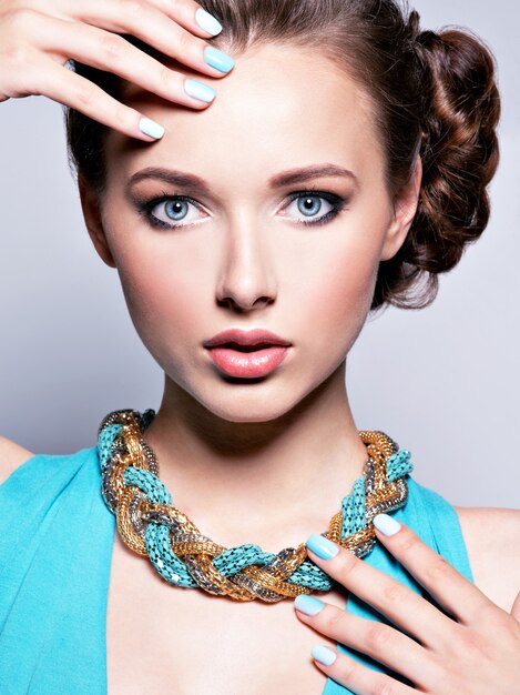 Young beautiful woman with jewelry. Girl Fashion  in blue dress wearing bijouterie. Attractive model with blue nails.