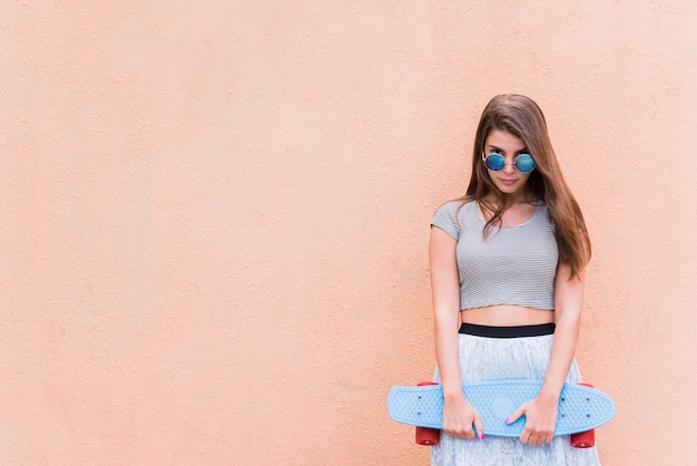 Free photo young beautiful woman with skateboard on pink background