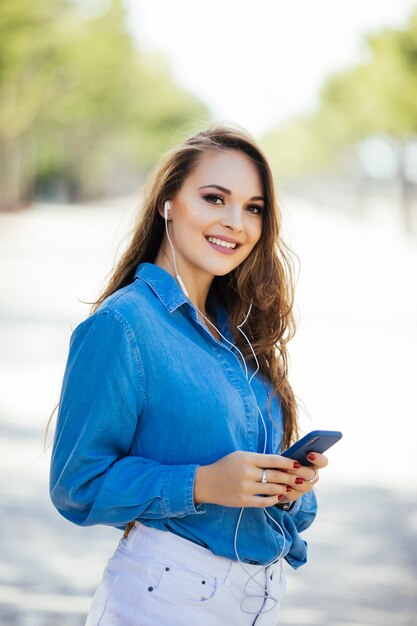 通りで屋外のスマートフォンを持つ若い美しい女性。ライフスタイルの肖像画