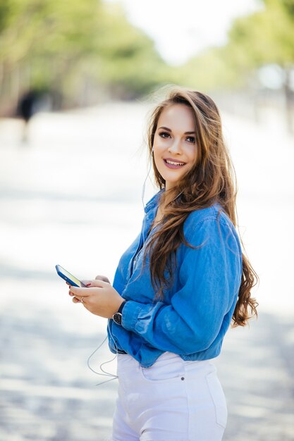 通りで屋外のスマートフォンを持つ若い美しい女性。ライフスタイルの肖像画