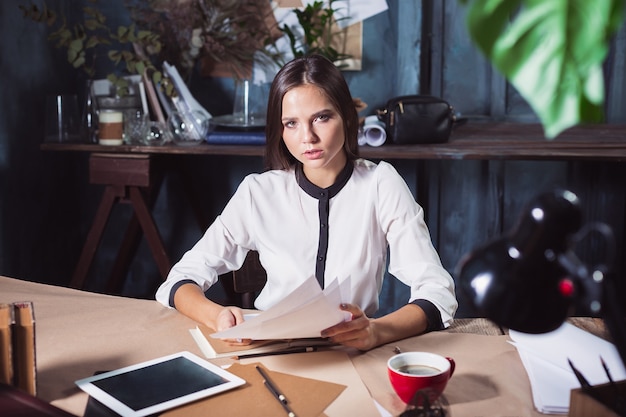 Молодая красивая женщина, работающая с чашкой кофе и ноутбуком в офисе на чердаке