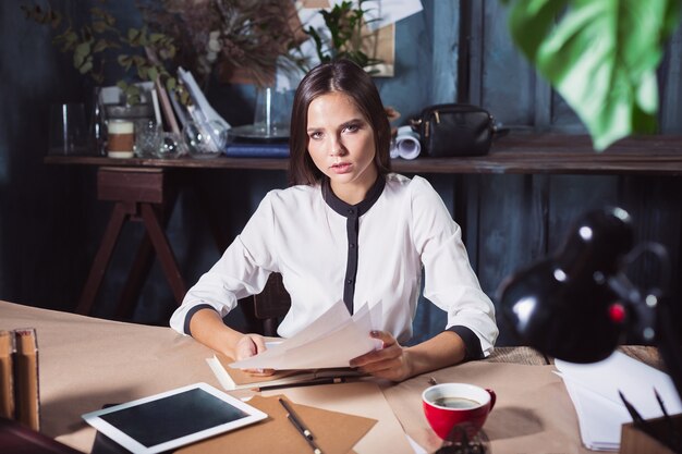 Young beautiful woman working with cup of coffee and notebook at loft office