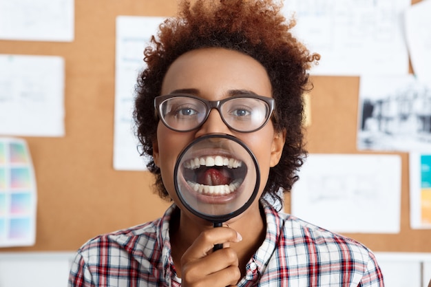 Young beautiful worker holding magnifier infront of mouth